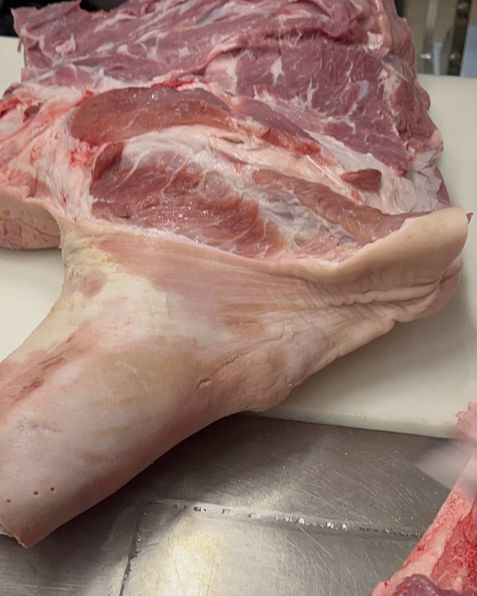 A section of pork on the block, belly and loin still joined