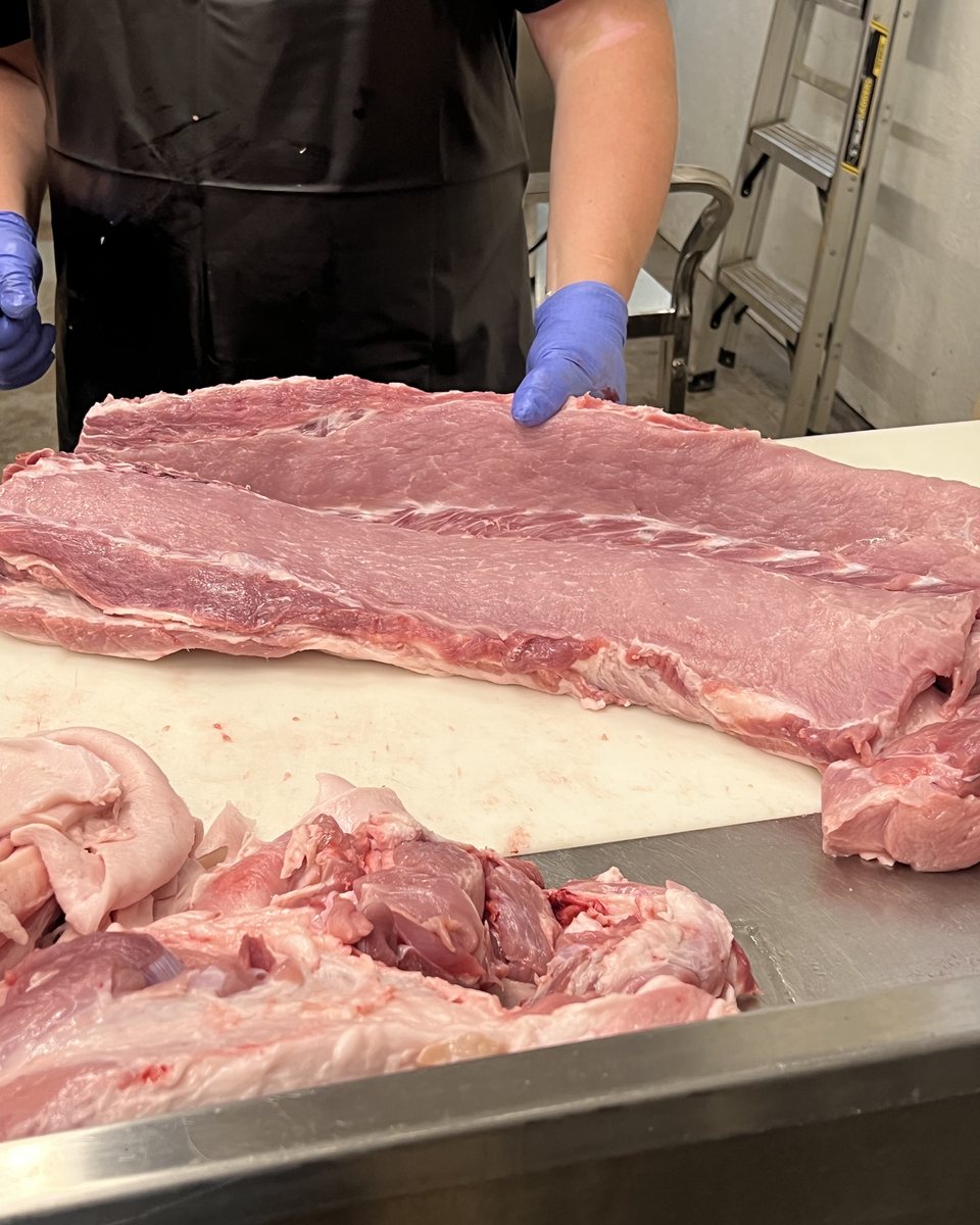 A pork loin seamed out to its full length on the cutting board