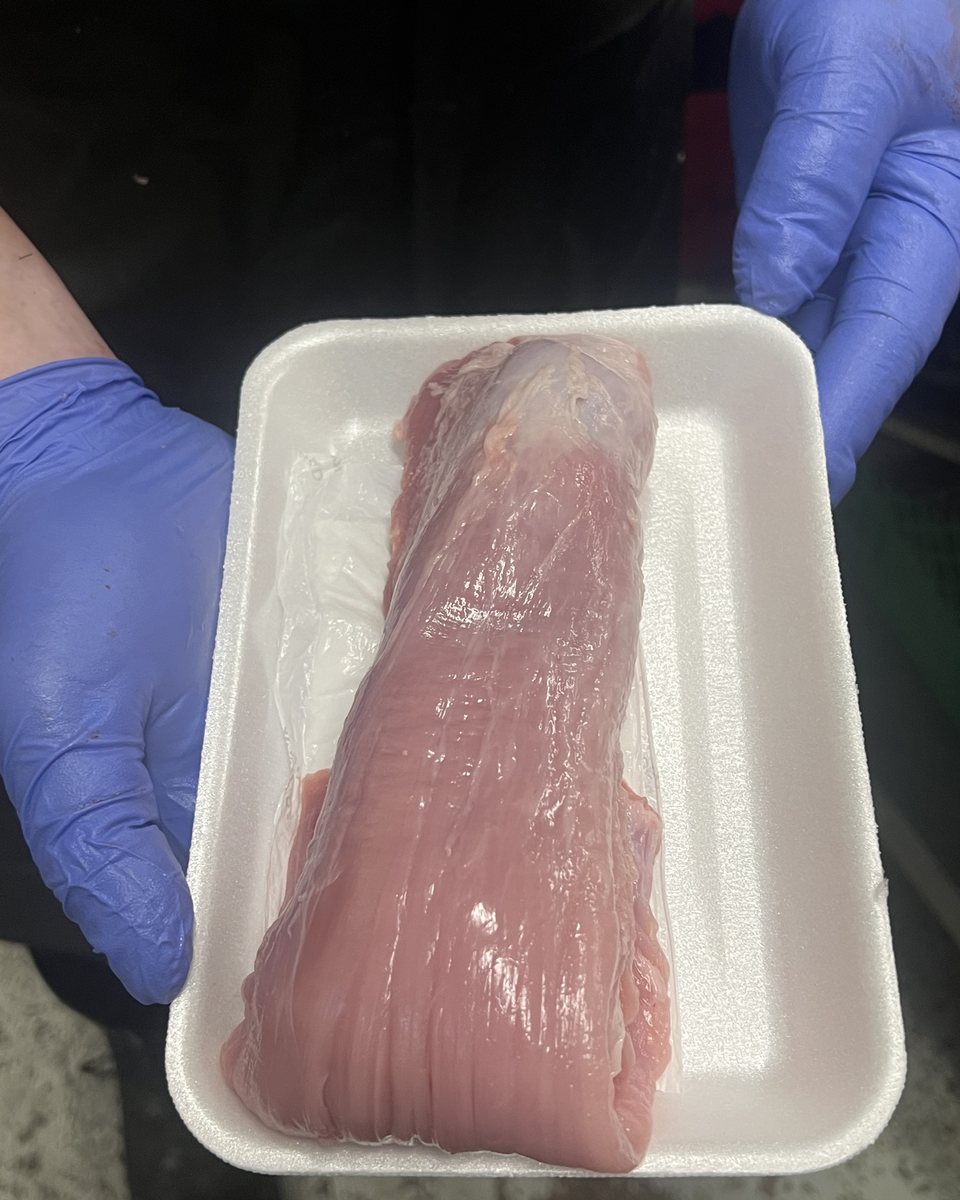 A wrapped pork tenderloin held in gloved hands