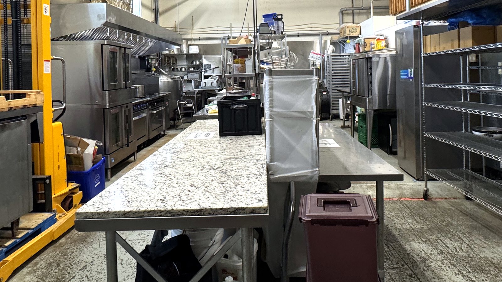 Full kitchen line with ovens and stainless prep tables at Butcher Bravo